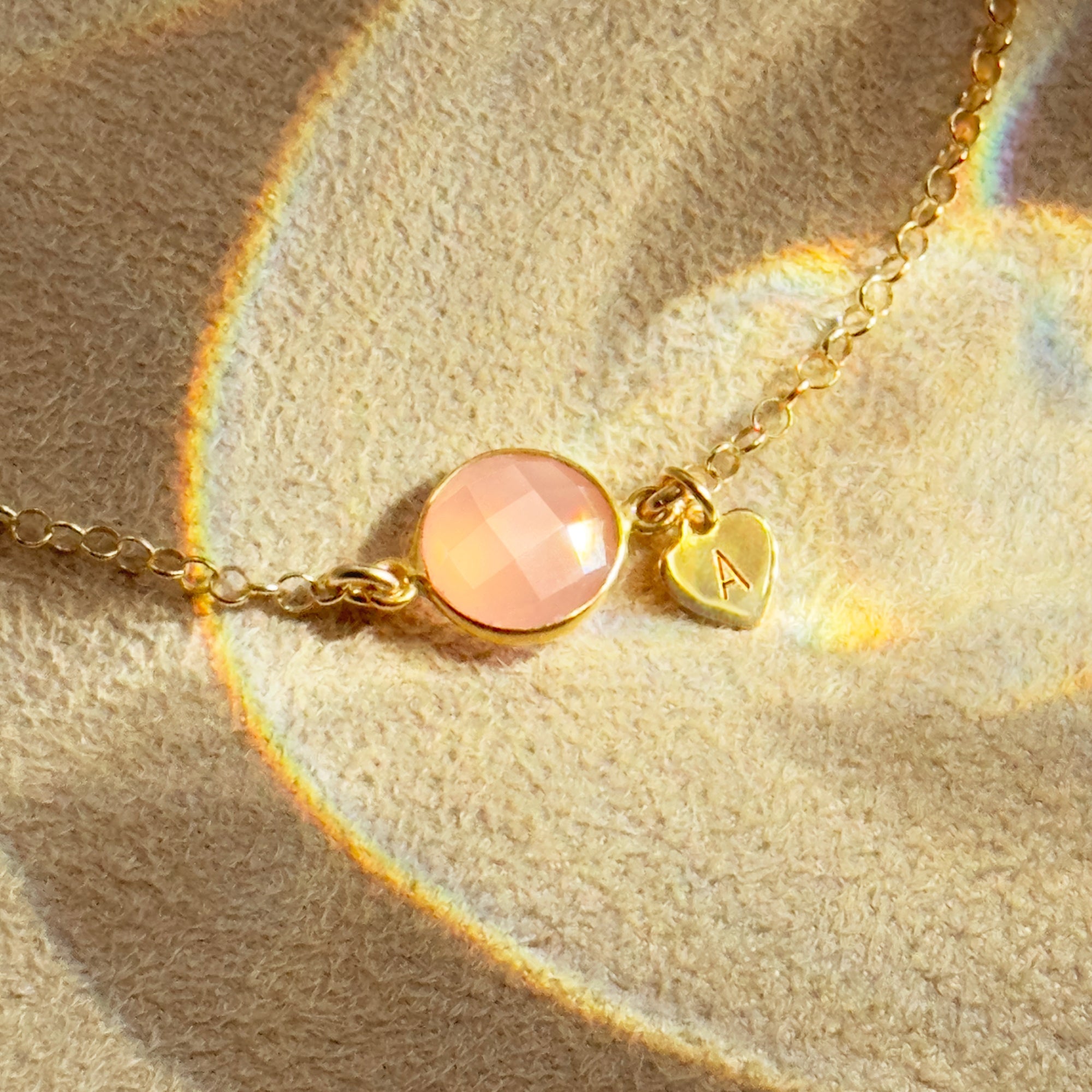 Delicate gold bracelet with faceted pink chalcedony October birthstone and personalized heart charm engraved with initial, dainty handmade jewelry gift for mom, daughter, or best friend.