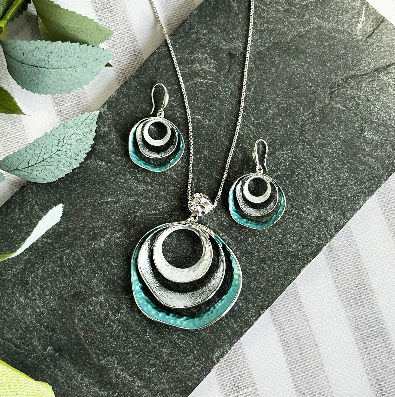 beautiful three-ring circles statement necklace and earrings set with silver and blue tones. Necklace is made with a steel cable chain and a zinc alloy pendant with a galvanic finish.