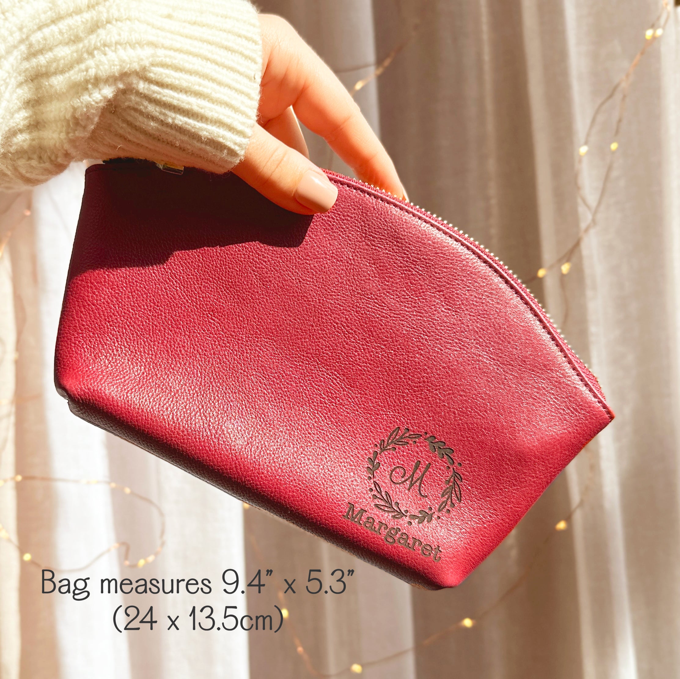 Custom leather toiletry pouch in raspberry red, engraved with floral wreath monogram and personalized name “Margaret.” This handmade travel organizer doubles as a stylish cosmetic case and durable everyday essentials bag. Designed with a secure zipper and compact size, it makes a unique personalized gift for bridesmaids, graduates, or frequent travelers. A chic leather pouch that blends beauty and functionality.