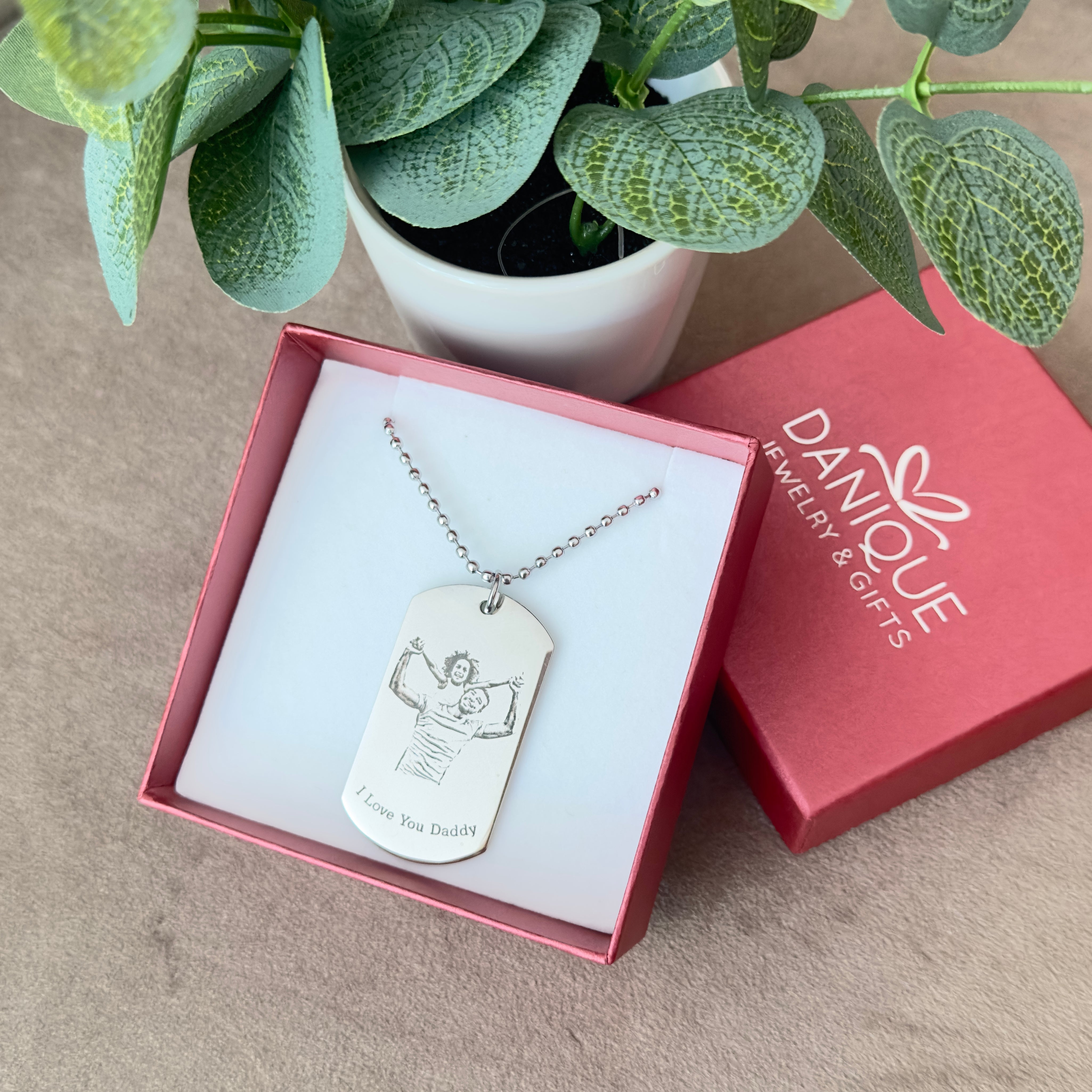 Engraved drawing dog tag necklace featuring custom artwork of a child and dad, displayed in a Danique Jewelry gift box with red packaging and silver ball chain. Personalized keepsake pendant crafted in stainless steel, engraved with “I Love You Daddy” message, making it a meaningful Father’s Day gift, birthday present, or Christmas surprise for dads, husbands, or grandfathers. Unique custom jewelry that captures family artwork or handwriting, ready to gift in premium packaging.