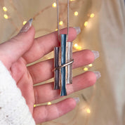 Model holding the Rose gold boho style geometric branch pendant necklace on beige background. statement jewelry, statement boho necklace, purple, blue, gray, rose. bohemian jewelry,