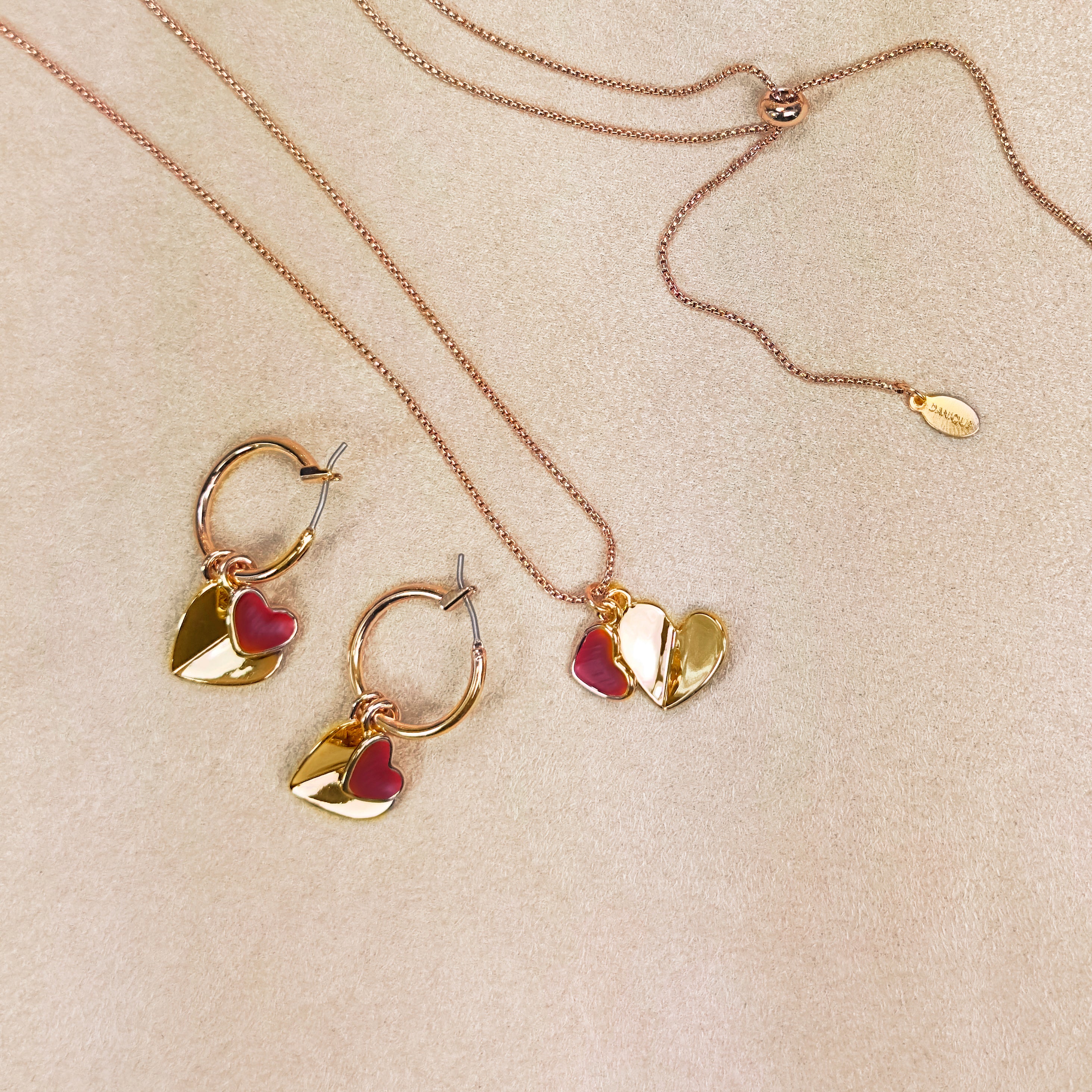 Rose gold double hearts pendant necklace and hoop dangle earrings set on beige background. Heart charms, heart necklace, statement necklace, bohemian jewelry, boho jewelry