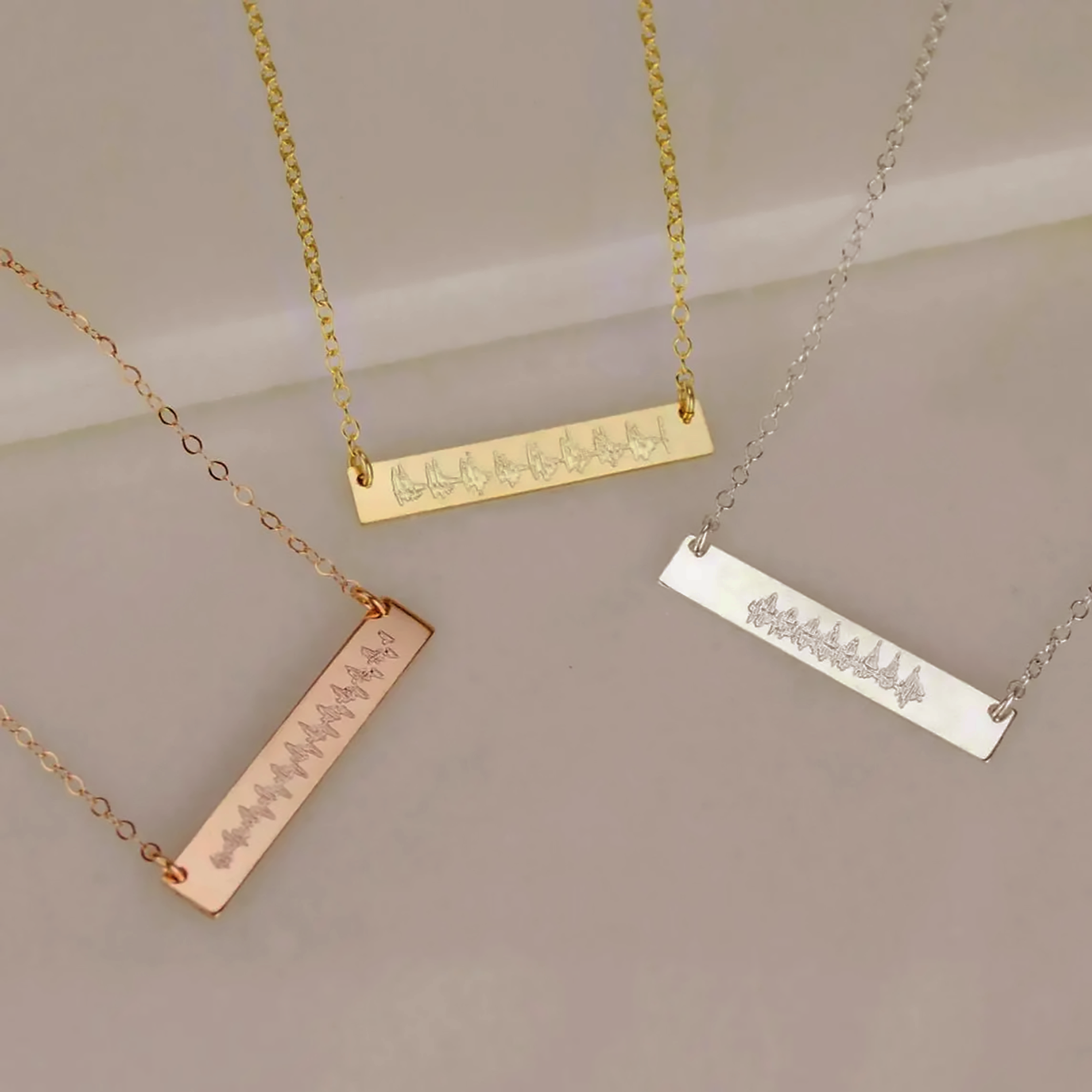 Three elegant engraved bar necklaces in rose gold, yellow gold, and sterling silver tones displayed side by side, featuring delicate soundwave designs symbolizing a baby’s first heartbeat. These heartbeat jewelry pieces are meaningful keepsakes for mothers and families, making a thoughtful pregnancy gift, remembrance jewelry, or personalized push present handcrafted with love and precision.