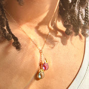 Model wearing gold two stone lariat necklace with ruby and blue topaz birthstones and hand stamped initial hearts. jewelry gift, necklace gift for her, anniversary gift, christmas gift, valentine's day gift, wedding jewelry, bridesmaid's jewelry, gift for mom, gift for wife, gift for girlfriend, gift for grandma, mother's day gift, july birthstone, december birthstone, birth month necklace, december necklace, july necklace