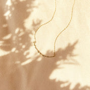 A gold morse code necklace with pearl spacers set on beige background. Couple gifts, couple initials, secret message gift, secret code gift, meaningful minimalist dainty necklaces for women, mothers day gift for her, personalized gift for women. Handmade beaded necklace gift. Custom beaded jewelry.