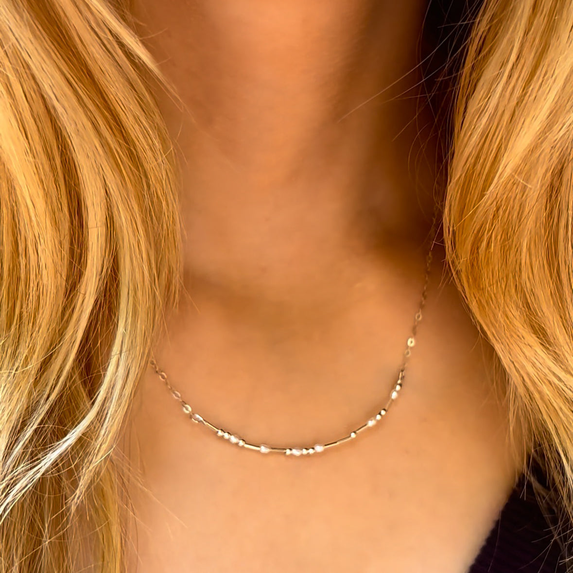 Model wears a subtle hidden message morse code necklace resting at the base of the neck, showing how the dainty bead pattern reads as chic minimalist jewelry from a distance. Choose gold filled or sterling silver for a refined friendship gift, birthday present, or daily layering piece. The adjustable 16–18 inch chain, lightweight feel, and handcrafted USA quality make this secret message necklace effortless and meaningful.