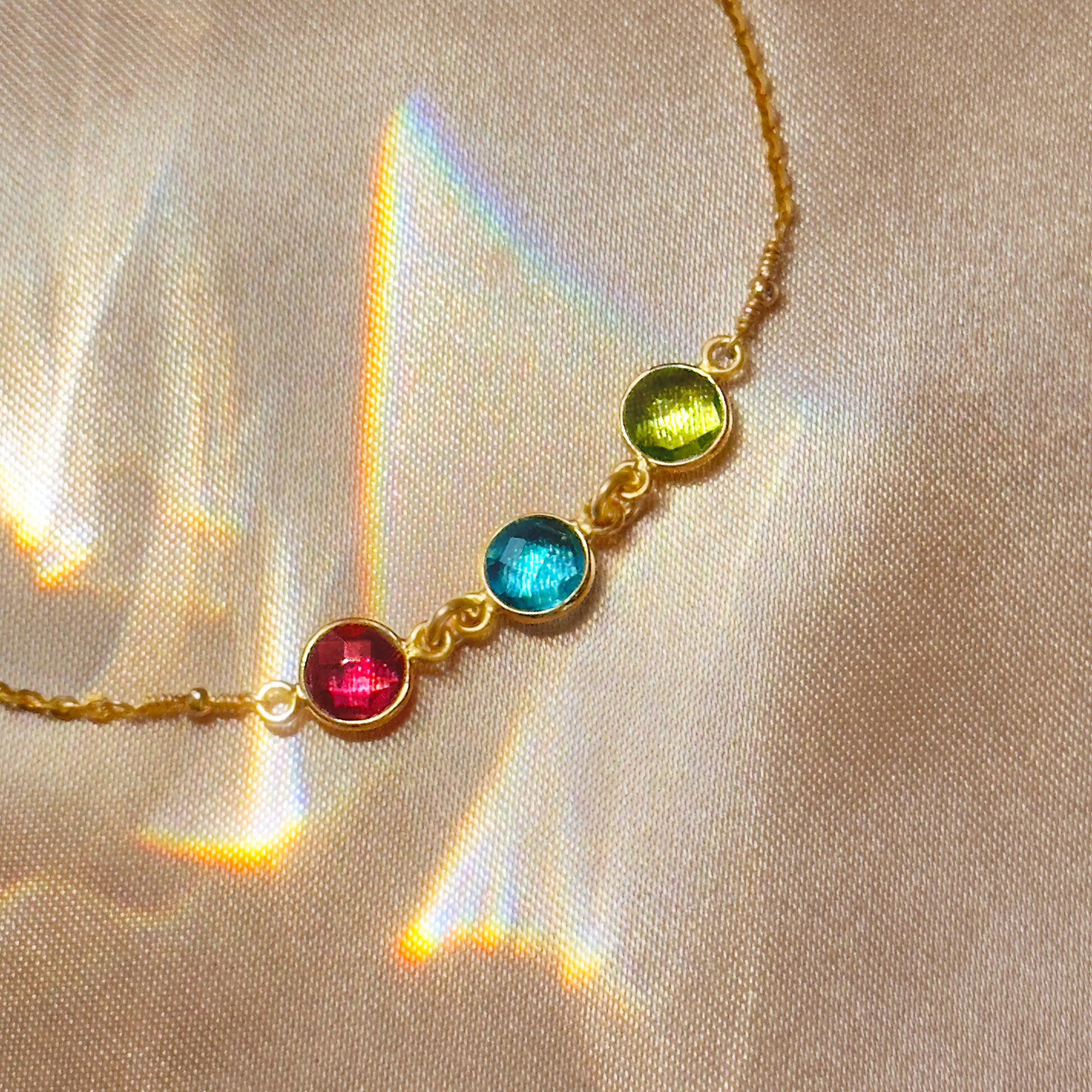 Detail shot of custom birthstone anklet with bezel-set stones in vibrant colors. Each gemstone symbolizes family, sisterhood, or friendship. A dainty and meaningful anklet perfect as a mom gift, grandma gift, or matching best friend jewelry. Available in sterling silver, gold filled, and rose gold filled. Adjustable or fixed fit for everyday wear and gifting occasions like Mother’s Day, birthdays, or Christmas.