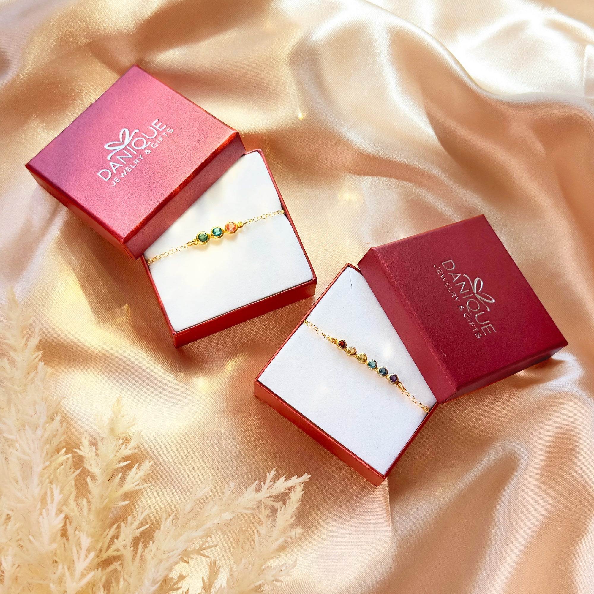 Personalized tiny birthstone bar bracelets in elegant red Danique Jewelry gift boxes, displayed on satin fabric. Each dainty bracelet features bezel-set gemstones arranged in a minimalist gold bar design, customizable with family birthstones. A meaningful push present bracelet for new moms, sentimental anniversary jewelry for wives, or a unique Christmas stocking stuffer for daughters and grandmothers. Handmade in sterling silver, yellow or rose gold filled with natural gemstones.