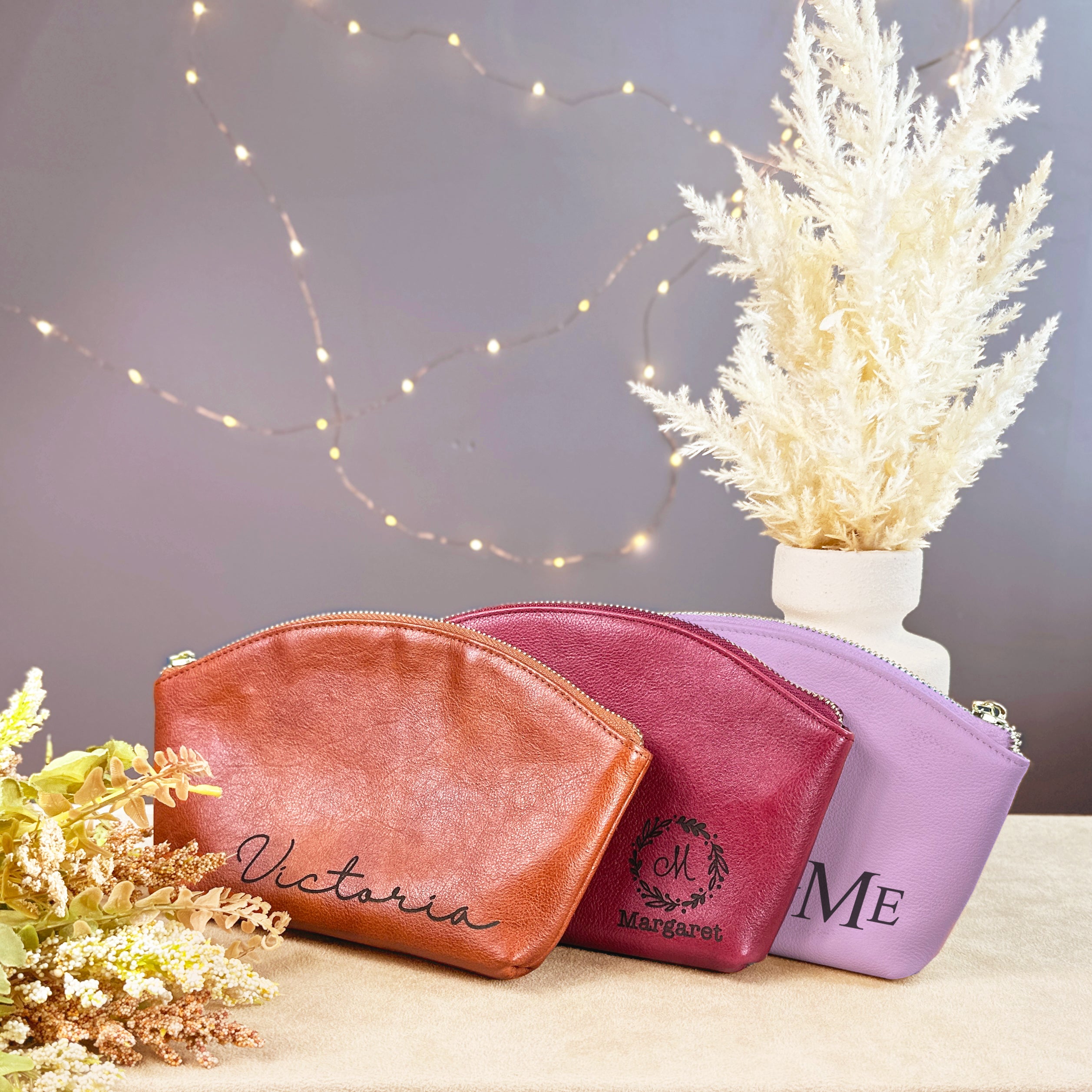 Set of three personalized leather cosmetic bags in honey brown, raspberry red, and lavender purple, each engraved with custom names and monograms. These stylish toiletry pouches feature a zippered closure and premium craftsmanship, perfect for bridesmaids, birthday gifts, or everyday travel organization. A versatile and elegant makeup bag collection for women who value personalization, durability, and timeless leather accessories.