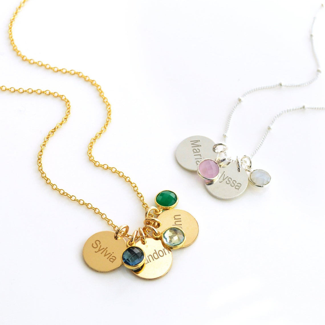 Gold filled cable chain necklace with three engraved disks and kyanite, sky blue quartz and green onyx birthstones. Sterling Silver necklace with satellite chain and two engraved name disks with pink chalcedony and moonstone birthstones.