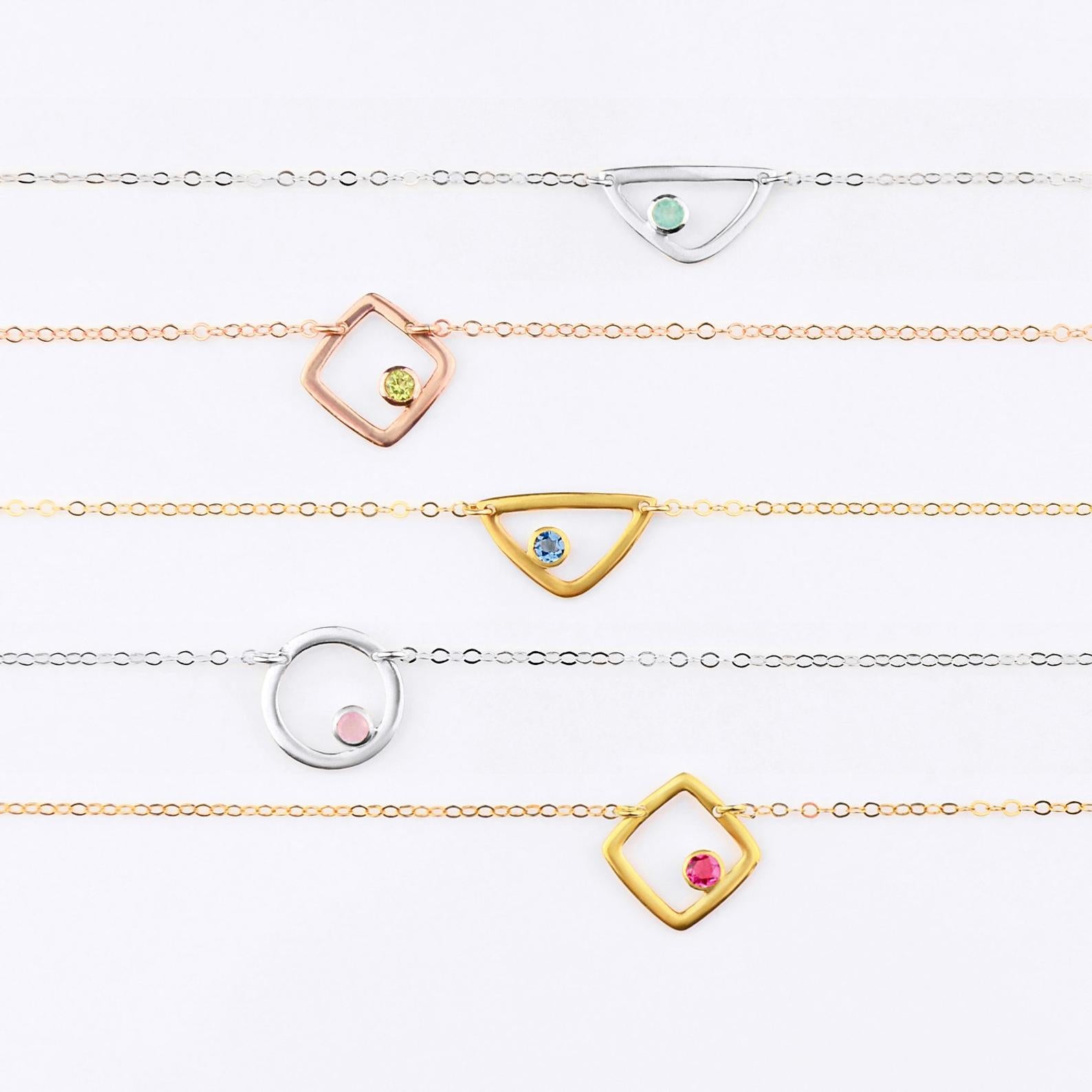 Eden bracelet open geometric series from top to bottom, sterling silver triangle with aqua chalcedony birthstone march birthstone. rose gold plated square with peridot birthstone august birthstone, gold plated triangle with iolite birthstone september birthstone, sterling silver circle charm with pink chalcedony birthstone october birthstone, gold plated square charm with ruby birthstone july birthstone on white background