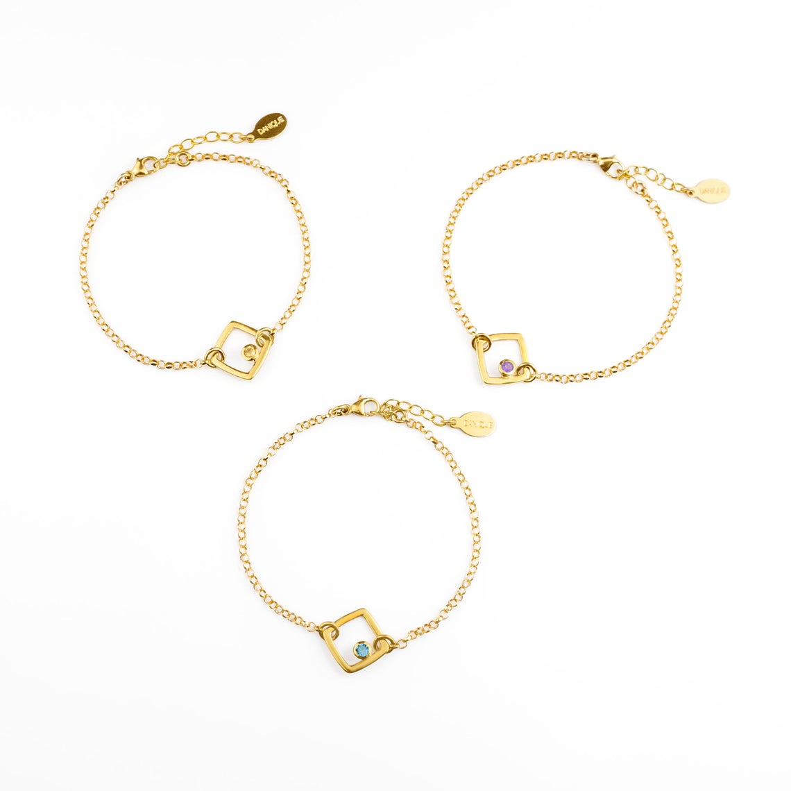 Three adjustable gold filled geometric square bracelets from top with citrine, purple amethyst, and kyanite birthstones on a white background.