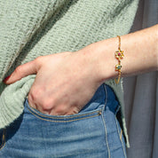 Model in green top is wearing a gold filled bloom mother of one bracelet with ruby and kyanite birthstones.