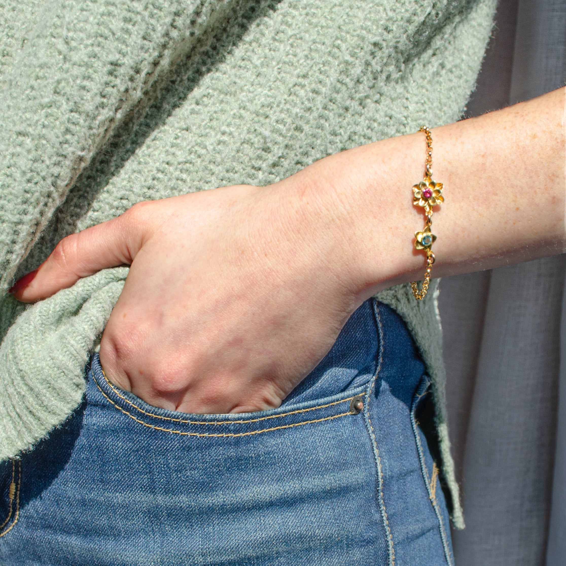 Model in green top is wearing a gold filled bloom mother of one bracelet with ruby and kyanite birthstones.