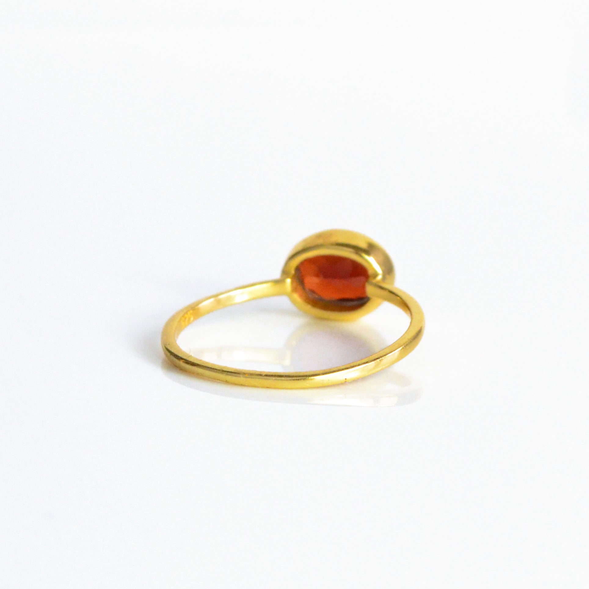 a rear view of the gold garnet ring shown on white background. stackable! Stacking rings, bezel set, small oval, tiny oval, dainty oval, birthstone rings, sterling silver stamp, birthstone ring, birthstone jewelry, red gemstone, red birthstone, january birthstone, january gemstone, stack set, stacking rings, gemstone ring, birthstone ring, mother's day gift for her, gift for mom, gift for fiance, gift for girlfriend, wedding jewelry, bridesmaid jewelry, anniversary jewelry, anniversary gift, birthday gift,