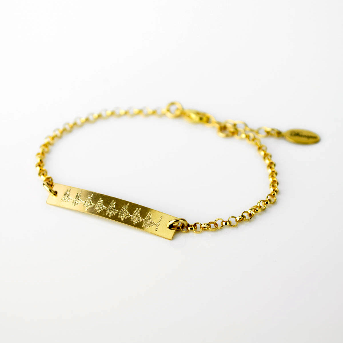 A gold-filled sonogram bracelet is laying flat against a white background. This heart beat jewelry can be engraved with a custom ekg, ultrasound or sonogram to capture your babys first signs of life! Ultrasound jewelry, sonogram jewelry, ekg jewelry