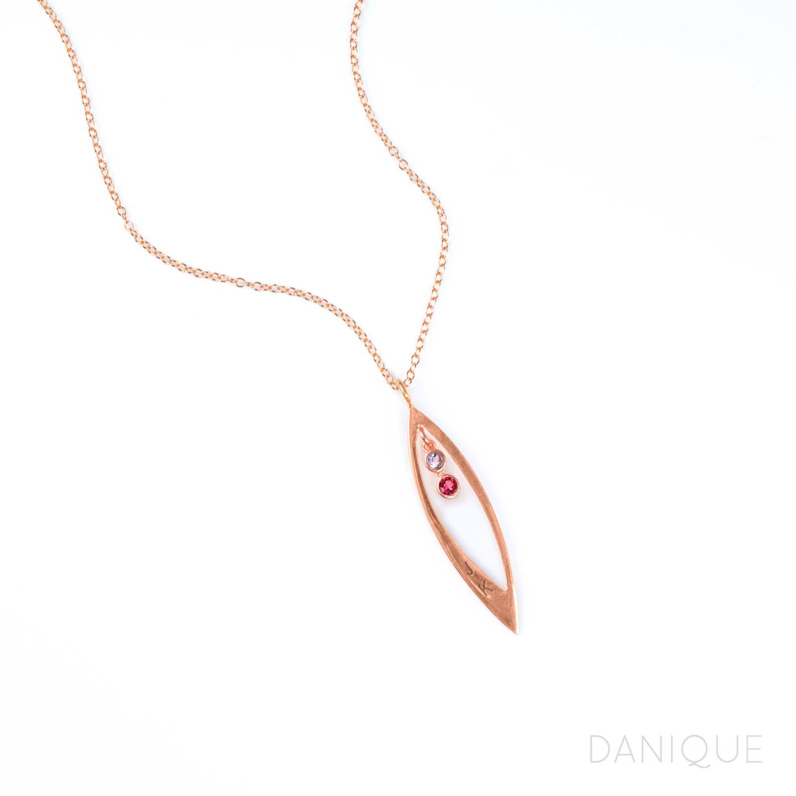 Rose gold filled mothers family tree necklace with open leaf pendant featuring purple amethyst and garnet birthstones with initial engraving on white background