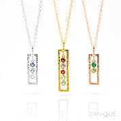 Three open frame vertical birthstone necklaces. One silver open frame necklace with kyanite, blue topaz and moonstone birthstones. Middle gold filled open frame necklace featuring 5 birthstones including garnet, purple amethyst, ruby, green amethyst and blue topaz. Last rose gold filled necklace with green onyx and peridot birthstones.