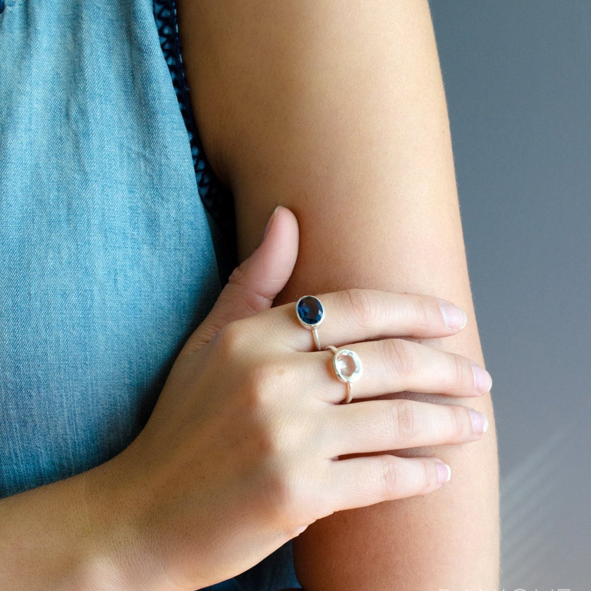 Model in blue top is wearing two sterling silver oval rings with kyanite and clear quartz birthstones. sterling silver clear quartz birthstone ring april birthstone gemstone ring april gemstone birthstone jewelry