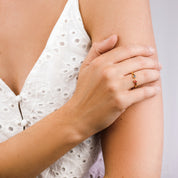 Model in white top is wearing a gold filled adjustable birthstone ring with kyanite and ruby gemstones.