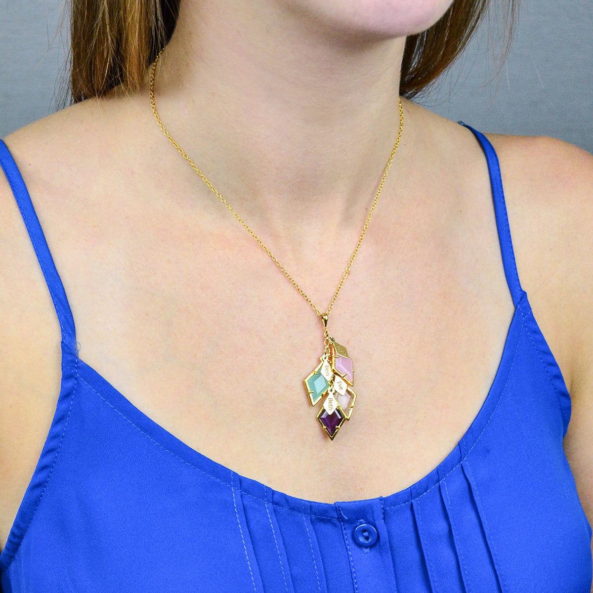Model in blue top is wearing our Mothers four stone and engraved full name tag cascading diamond shape necklace with pink chalcedony, aqua chalcedony, moonstone, and purple amethyst.