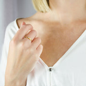Model is wearing one gold leaf birthstone ring with custom initial engraving.