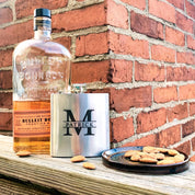 Three custom engraved stainless steel flasks in with different designs: name and message monogram design next to bourbon bottle and almonds. Fantastic personalized gift for party, wedding, christmas, birthday.