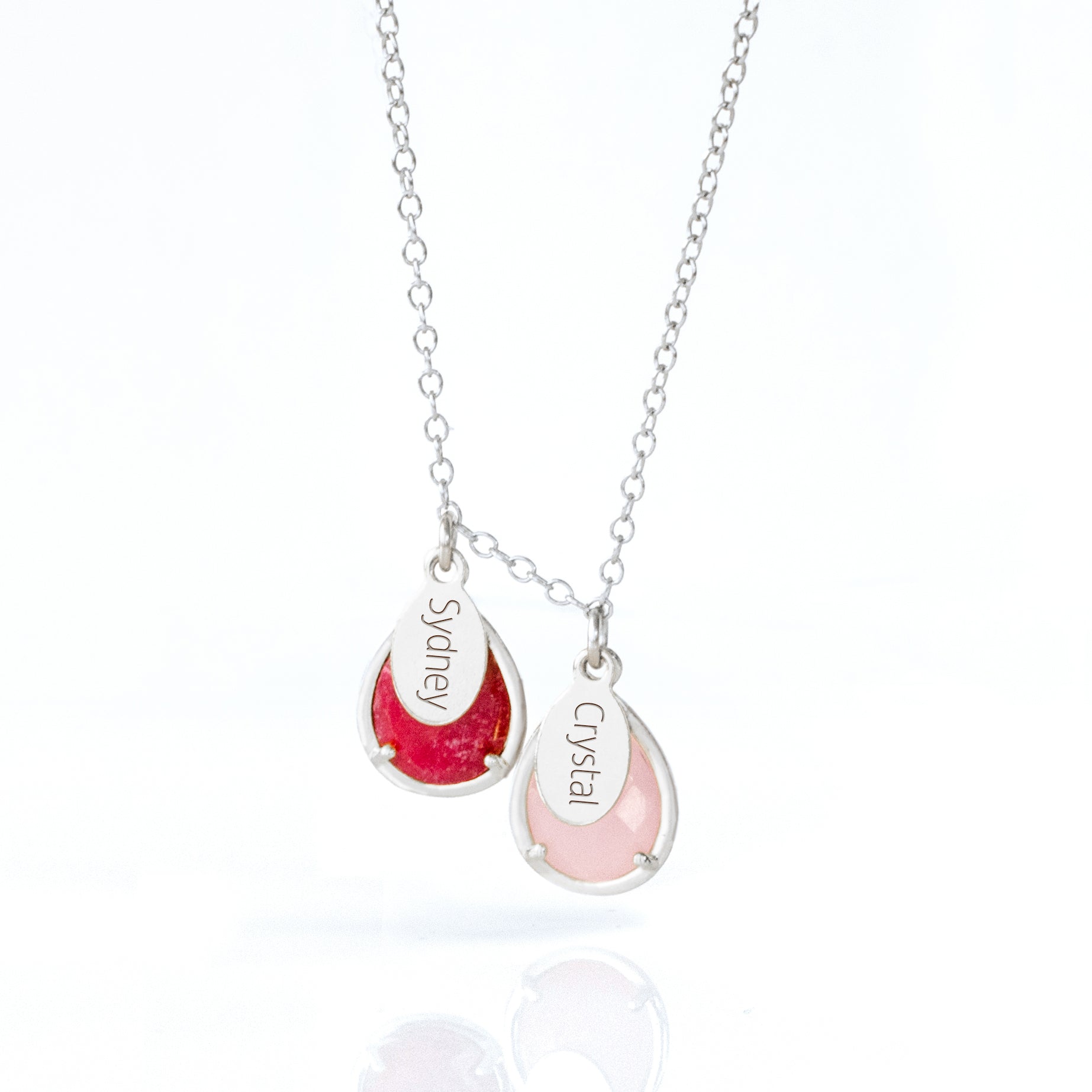 Silver prong teardrop necklace with two birthstones, ruby and pink chalcedony with engraved name tags.