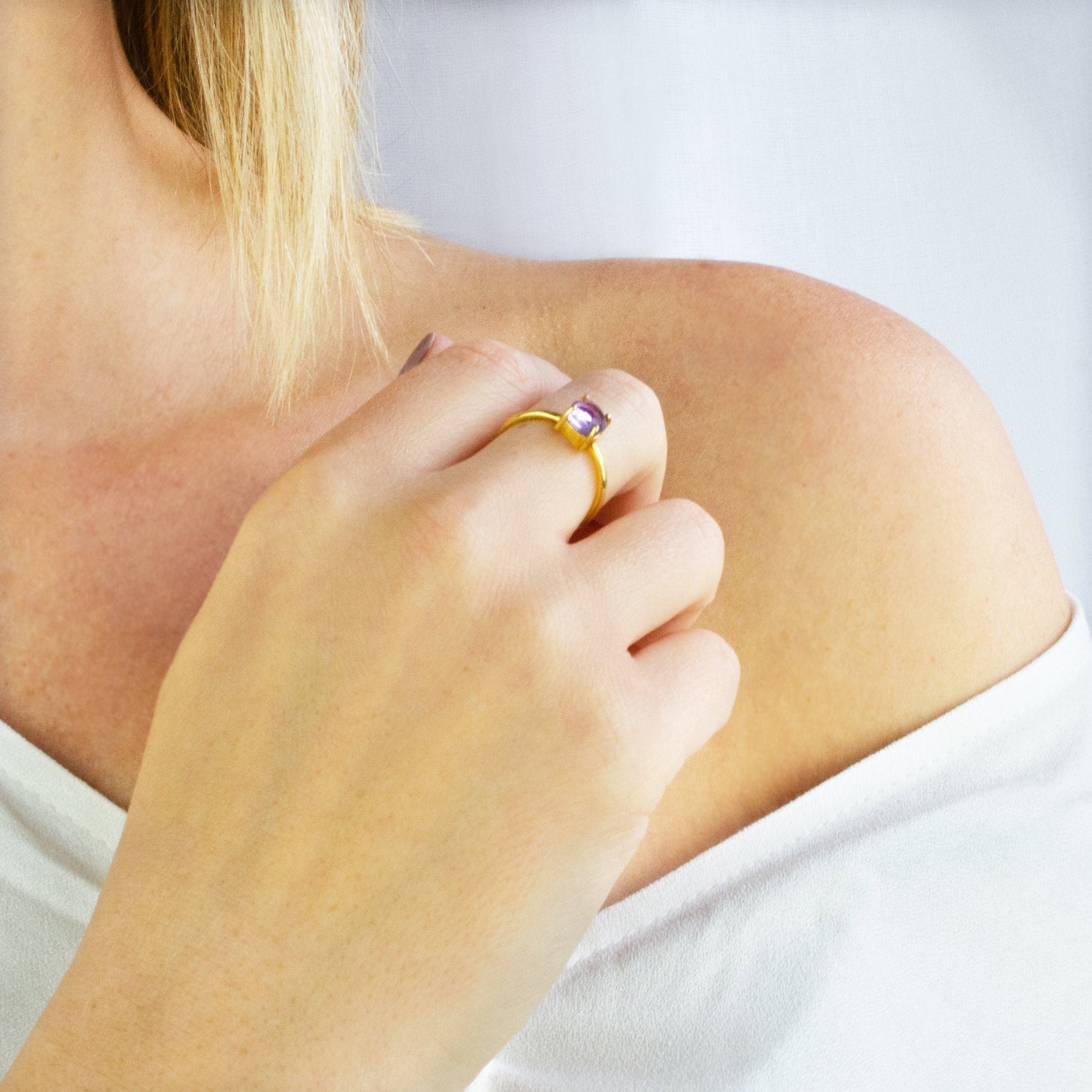 Model in white top is wearing a gold plated purple amethyst stackable prong set round ring. Birthstone jewelry, birthstone ring, stacking rings, ring stack, gemstone ring, gemstone rings