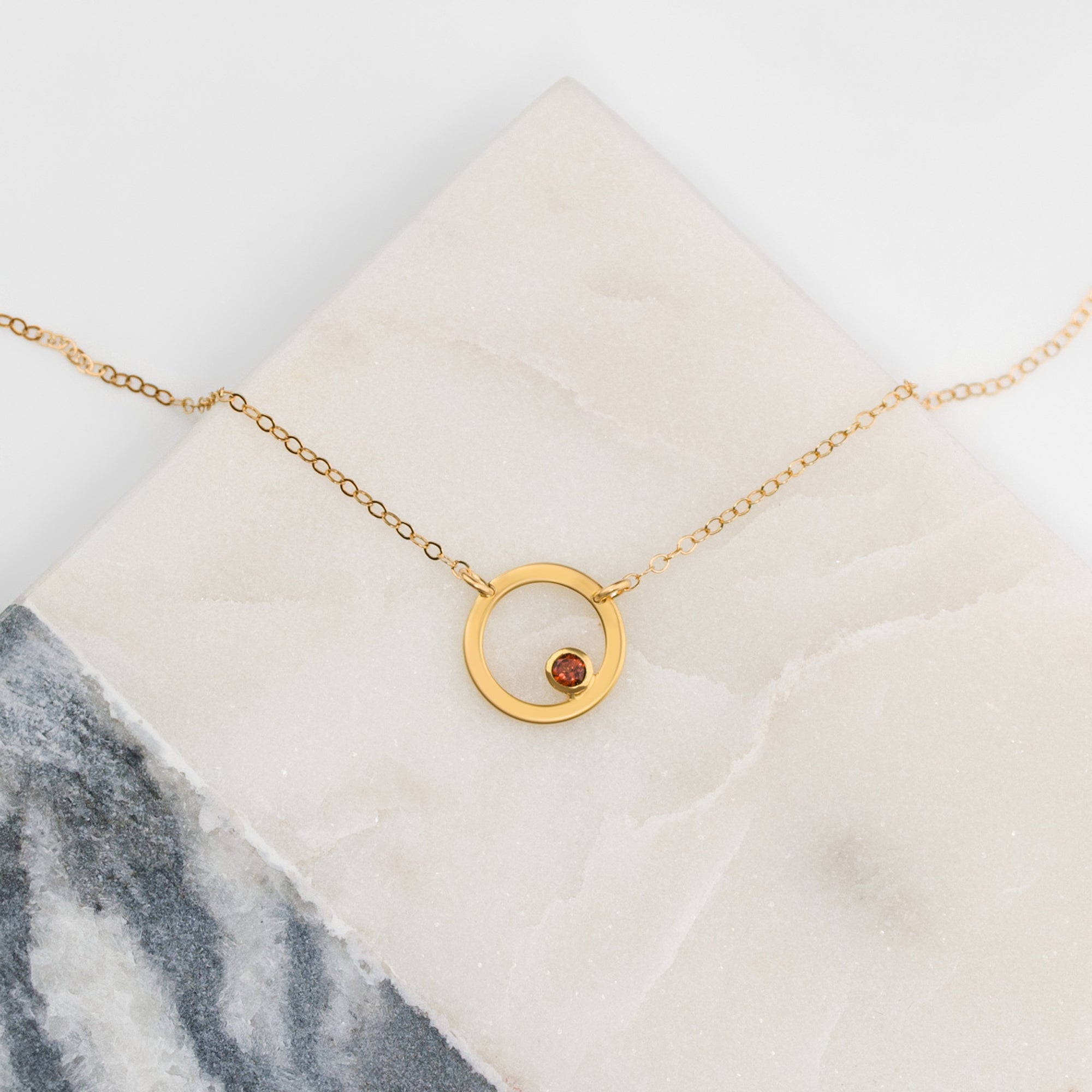 Single gold filled open circle geometric necklace with garnet birthstone. January birthstone.