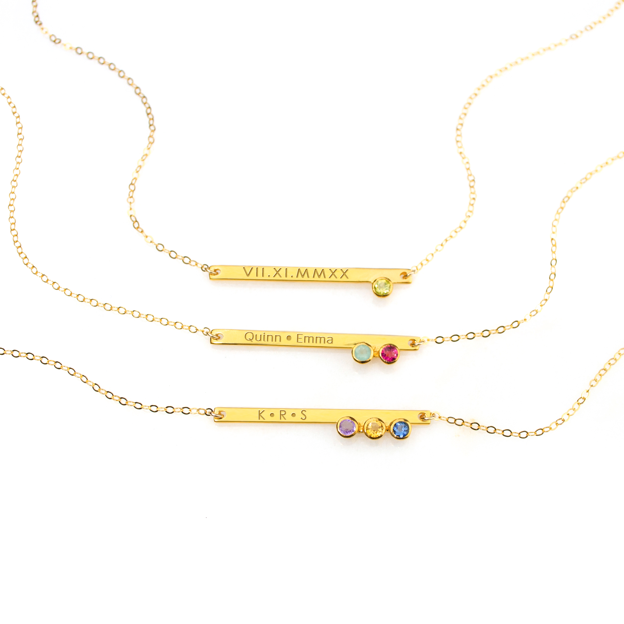 Gold plated skinny bar with 1 peridot gemstone and roman numerals, center necklace has two names engraved with aqua chalcedony and ruby gemstones, last necklace has initial engraved with the purple amethyst, citrine and iolite birthstones.