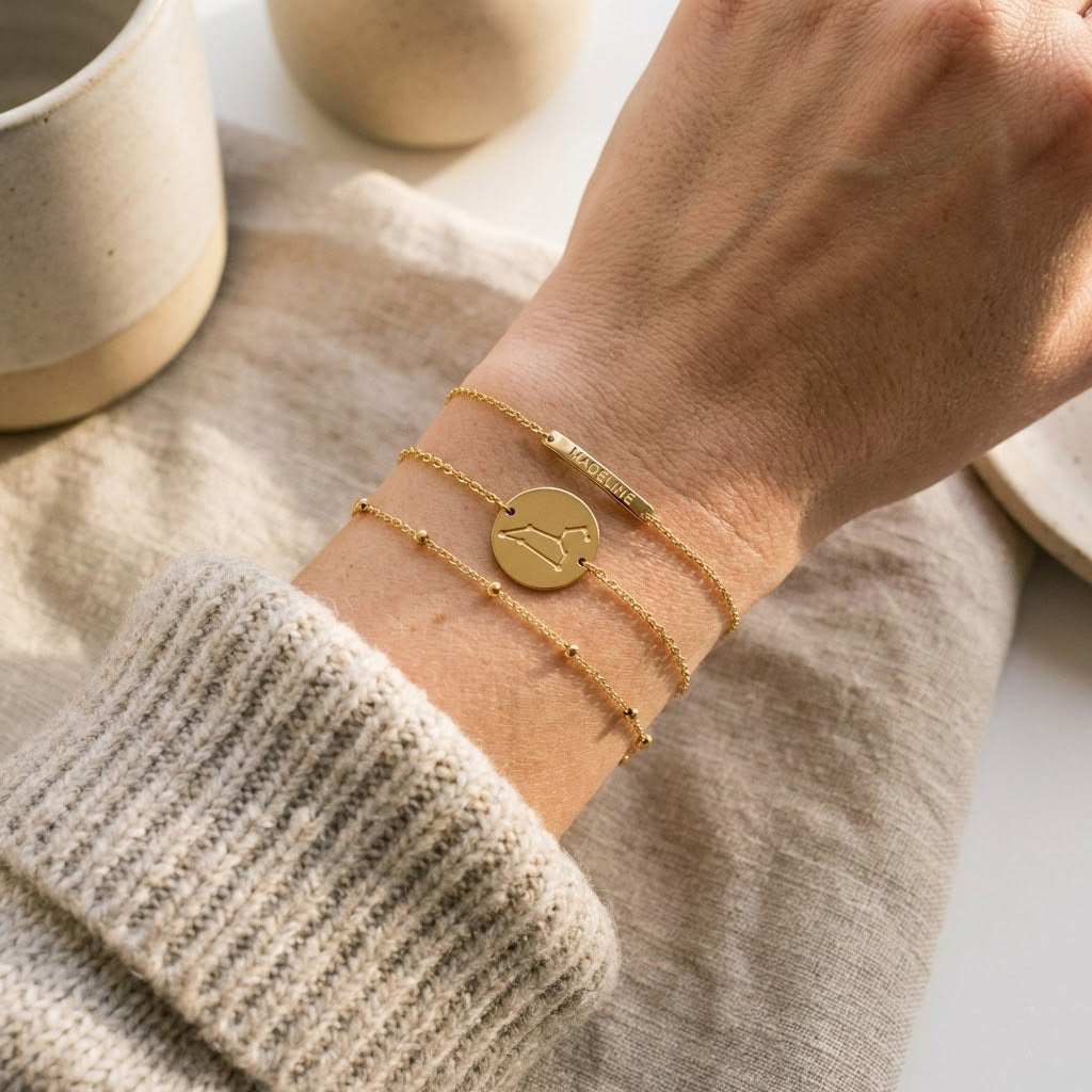 Minimalist gold zodiac constellation bracelet engraved with star pattern layered with delicate chain bracelets on a model’s wrist, elegant celestial astrology jewelry styling gift for zodiac lovers