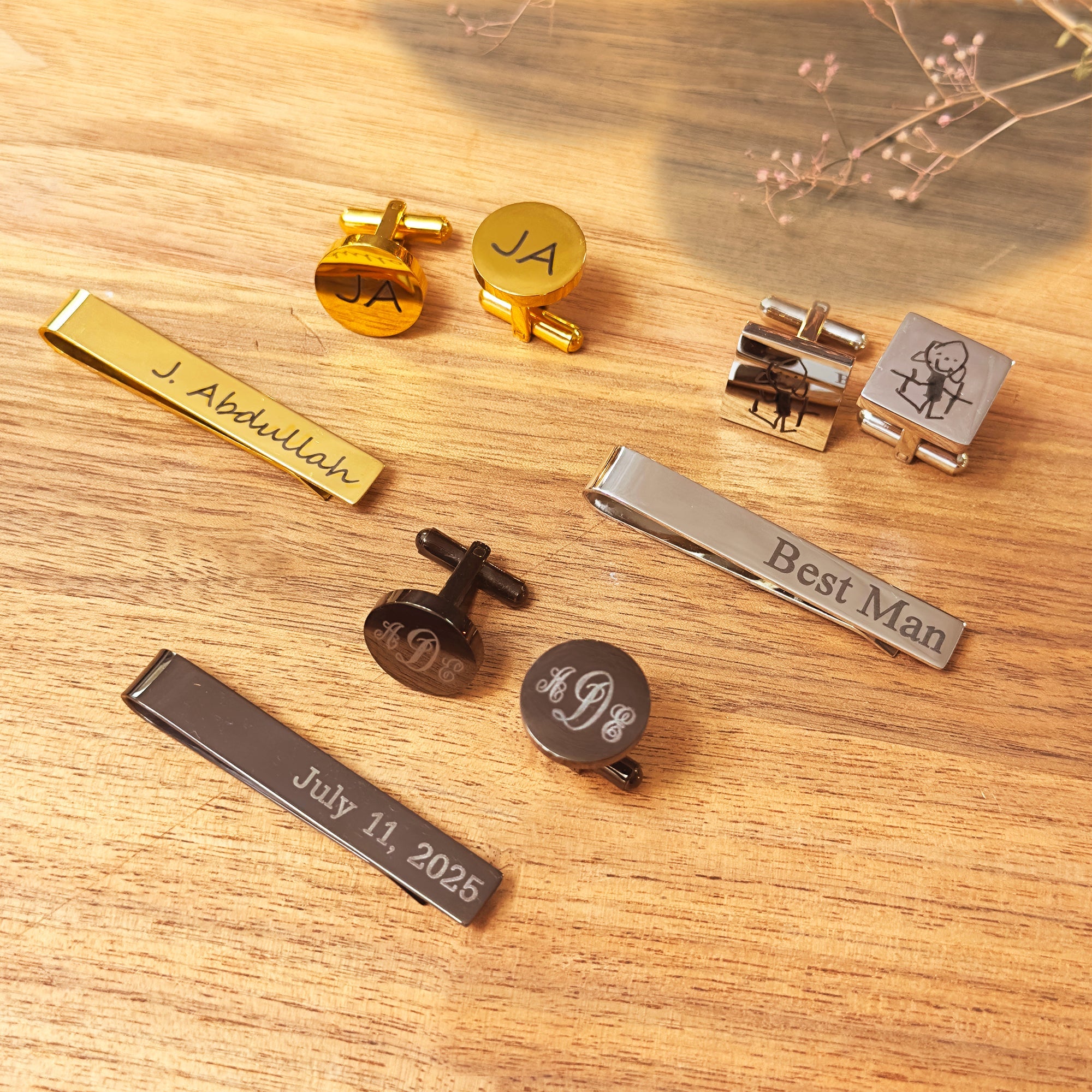 Personalized groomsmen gift sets featuring custom engraved tie clips and cufflinks. Metal finishes include gold, silver, and black with options for names, dates, and custom art.