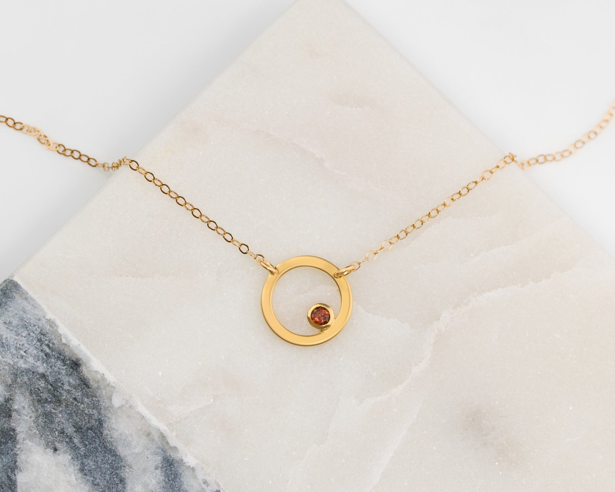 Mother holding young child while wearing a minimalist birthstone circle necklace in sterling silver, a sentimental custom pendant for moms, styled in soft neutral tones for an elegant family portrait.