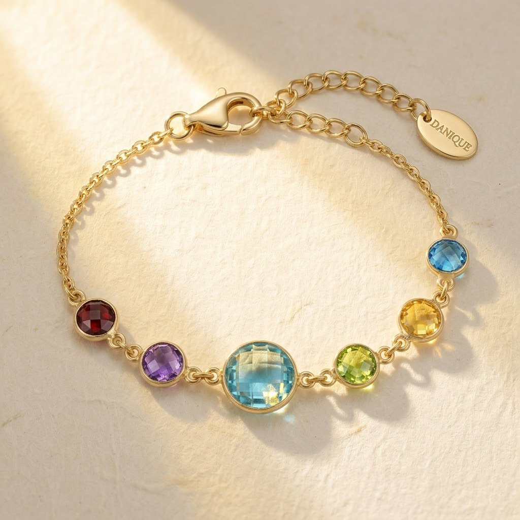 Custom birthstone mom bracelet with colorful gemstone charms representing children, featuring a larger center stone for mom on a delicate gold chain.