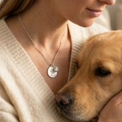 Hand holding personalized paw print necklace with birthstone charm, dog mom gift