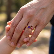 Mother wearing a personalized four birthstone family ring with colorful gemstones on her hand.
