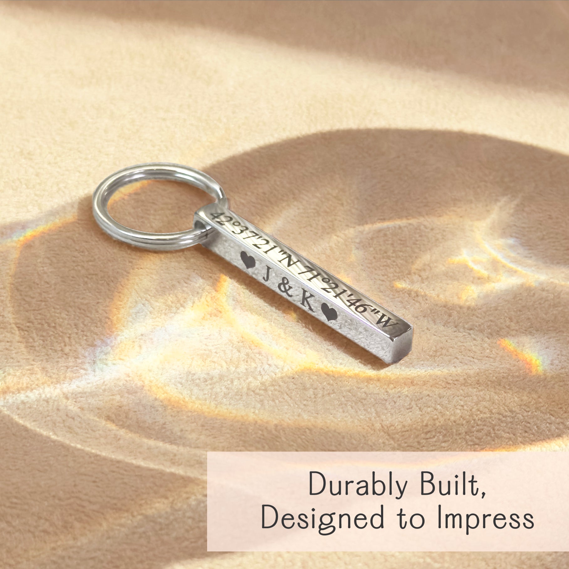 Close-up of a silver stainless steel 3D bar keychain resting in warm light, showing crisp laser engraving along the edge. Minimalist style highlights reflective finish, readable lettering, and modern proportions—great for roman numeral keychain or latitude/longitude GPS coordinates gift; durable everyday carry accessory for him or her.