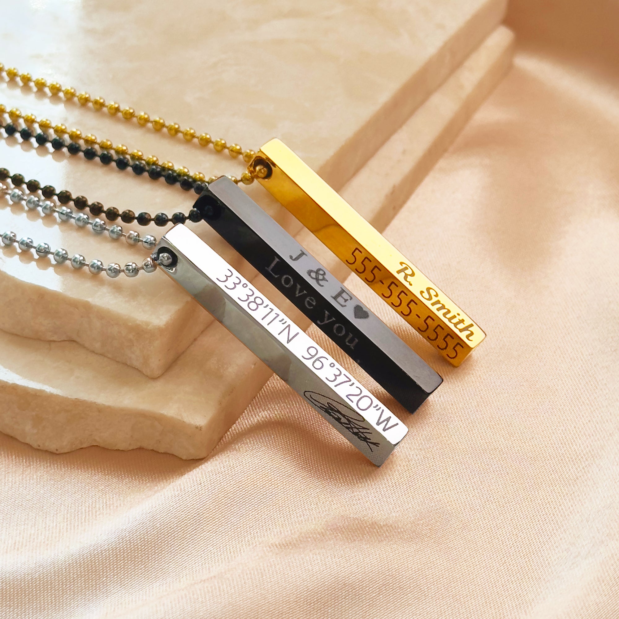 Custom engraved 3D bar necklaces for men in stainless steel, gold and black finishes displayed on soft satin, showing personalized vertical bar pendants with custom coordinates, names, Roman numerals and fingerprint engraving. Modern men’s jewelry gift for boyfriend, husband or dad, durable masculine bar pendant with four-sided engraving options for meaningful everyday wear.