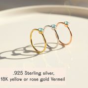 set of dainty stackable gemstone rings displayed on soft champagne satin fabric, featuring aqua chalcedony and other birthstones bezel set in thin gold vermeil bands, highlighting the elegant minimalist design ideal for stacking or wearing alone, available in all birthstones for custom mom ring stacks or meaningful birthday gifts, handcrafted in sterling silver or gold vermeil with delicate round stones perfect for everyday wear or special gifting
