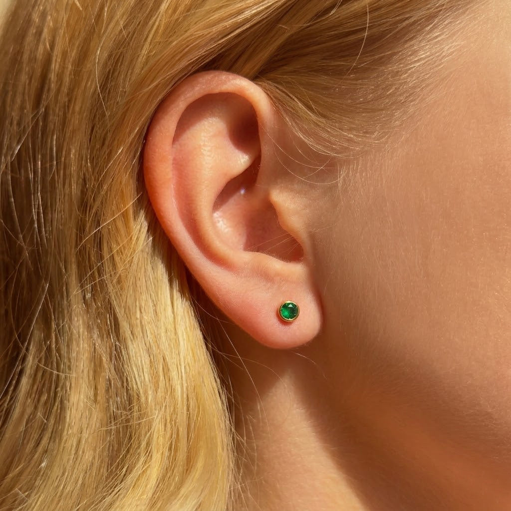 Green birthstone stud earring worn on the ear showing tiny minimalist gemstone size for everyday wear