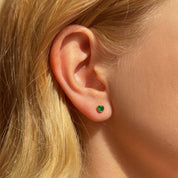 Green birthstone stud earring worn on the ear showing tiny minimalist gemstone size for everyday wear