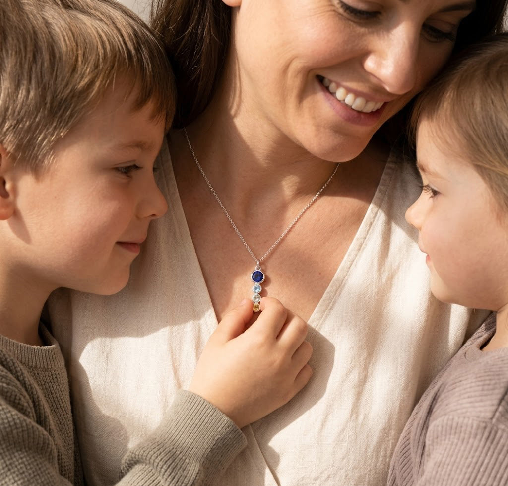 Mom wearing a custom birthstone necklace with her children, showing a sentimental family necklace made with birthstones for loved ones.