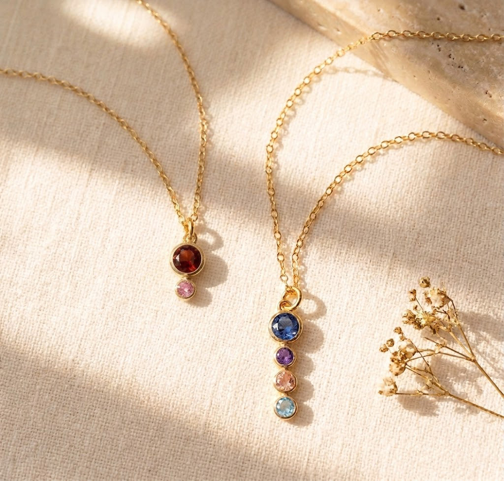 Personalized birthstone necklace displayed on warm fabric, featuring a larger mom stone with smaller children’s birthstones on a delicate chain.