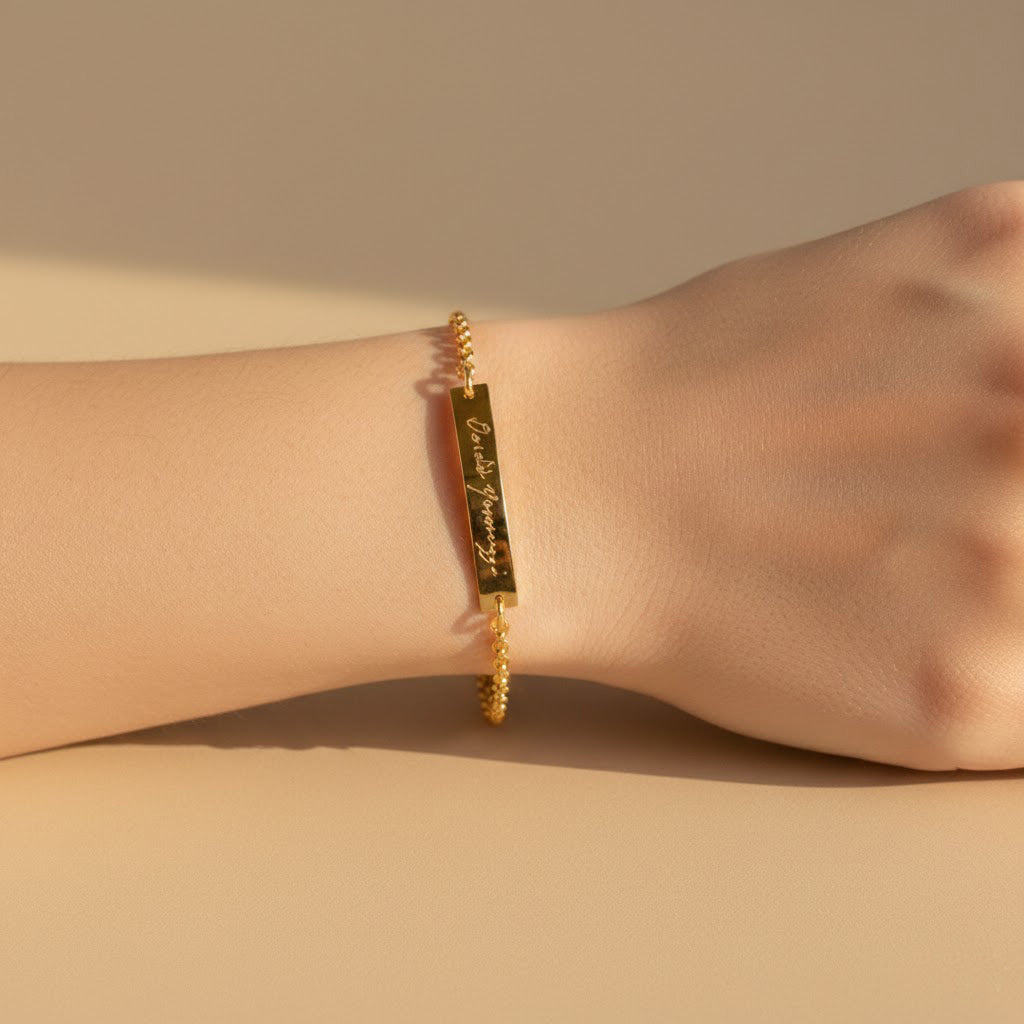Model in cream top is wearing the engraved gold filled bar bracelet.