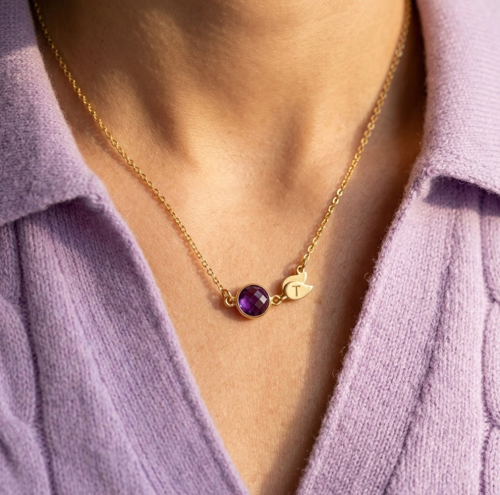 Woman wearing dainty birthstone necklace with engraved initial charm
