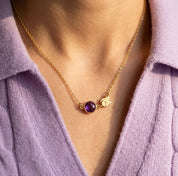 Woman wearing dainty birthstone necklace with engraved initial charm