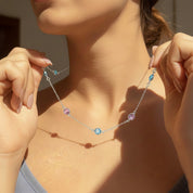 Model wearing Taylor Swift–inspired warm-tone custom birthstone necklace with stations featuring July Ruby, September Sapphire, January Garnet, and October Opal along a gold chain. A meaningful everyday necklace that can be personalized with children's or loved ones’ birth months, perfect for Swifties, moms, grandmas, or friends celebrating birthdays, Mother’s Day, or special milestones with sentimental gemstone jewelry.