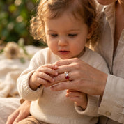 Mom holding her child while wearing a custom two birthstone family ring.
