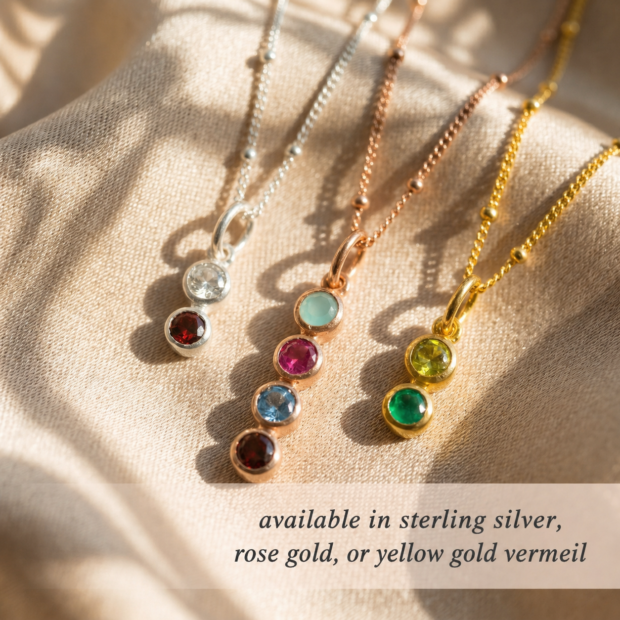 Three necklaces with colored gemstones on a beige fabric background. Each necklace is crafted with 925 sterling silver, 18k rose gold vermeil, or 18k yellow gold vermeil.